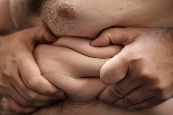 Мужские руки держат избыточный жир на животе, крупным планом. Толстяк. Понятие здорового образа жизни . — стоковое фото