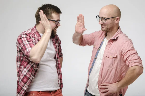 Two friendly smiling men greet each other and give a high five.