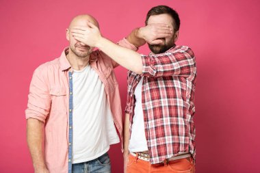 Rahat giyimli iki beyaz adam elleriyle gözlerini kapadı..