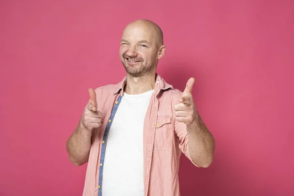 Retrato de um homem sorrindo positivo com restolho, apontando com dois dedos indicador para a câmera e olhando com os olhos espremidos — Fotografia de Stock