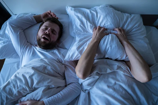 La mujer está estresada, se cubre la cara con una almohada, no puede quedarse dormida porque su marido ronca. Concepto de insomnio femenino . — Foto de Stock