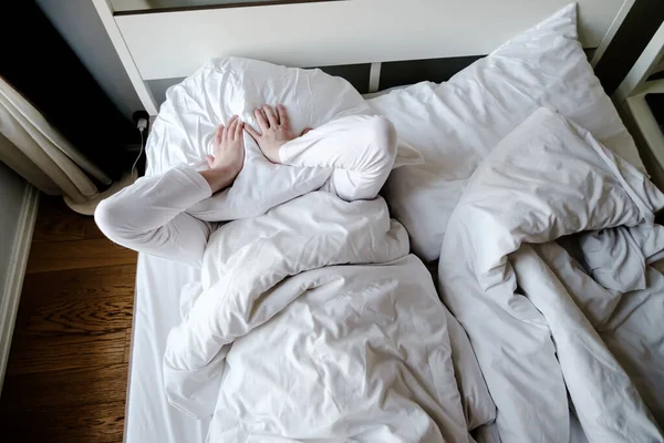 El hombre no puede quedarse dormido debido al ruido, está cansado y en estrés cubre la cabeza con una almohada. Concepto de insomnio . — Foto de Stock