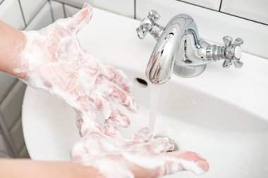 Washing hands with soap suds, under running water, in the bathroom. Top view.