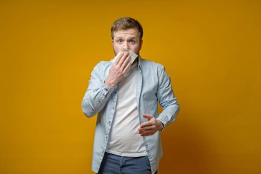 Adam öksürmek ya da hapşırmak üzere ve korkmuş bir şekilde ağzı peçeteyle örtüyor. Virüsün yayılması kavramı.