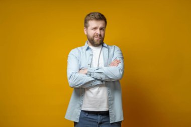 Yüzünde garip bir ifade olan adam kollarını kavuşturmuş, bir gözünü kapatmış ve kameraya bakıyor..