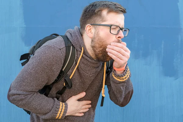 L'uomo barbuto tossisce, copre la bocca con il palmo della mano e tiene la mano sul petto, nel dolore. Concetto di diffusione del virus . — Foto Stock