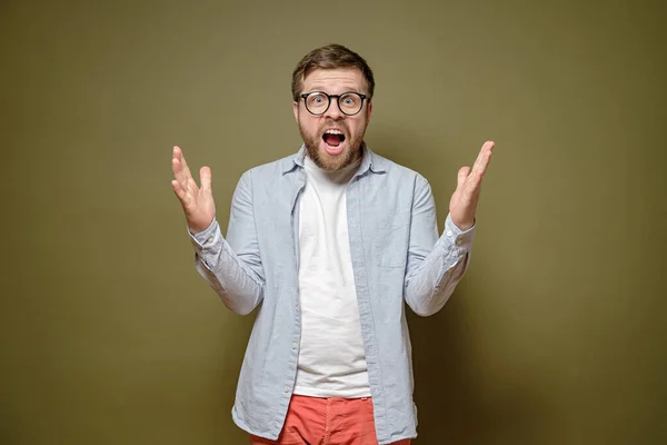 Hombre caucásico es gratamente sorprendido y sorprendido por una sorpresa inesperada, grita alegremente y hace un gesto con las manos . — Foto de Stock