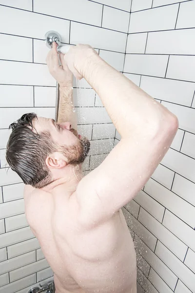 Hombre caucásico está tratando de reparar una regadera en un cuarto de baño que ha roto o agua fría se ha derramado fuera de ella . — Foto de Stock