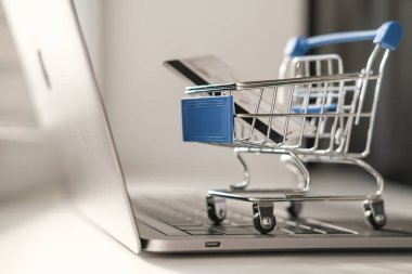 Süpermarketten gelen küçük bir tramvay dizüstü bilgisayarın üzerinde duruyor. Karantina sırasında online alışveriş kavramı 