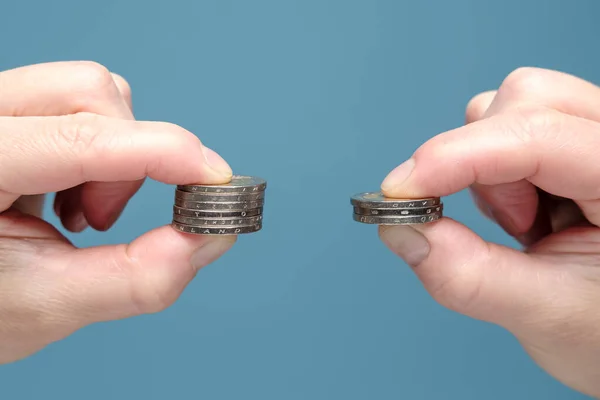 Hände vergleichen zwei Stapel von Münzen unterschiedlicher Größe, was auf eine Verschlechterung der finanziellen Situation hindeutet. Wirtschaftskonzept. Nahaufnahme. — Stockfoto