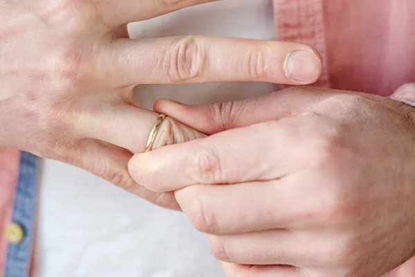 Мужчина снимает с пальца золотое обручальное кольцо. Концепция семейной ссоры, развода или предательства . — стоковое фото