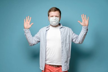 Tıbbi maskeli bir adam dokunulup el kaldırıldığında virüsün yayılmasını önlemek istiyor. Sağlık kavramı.