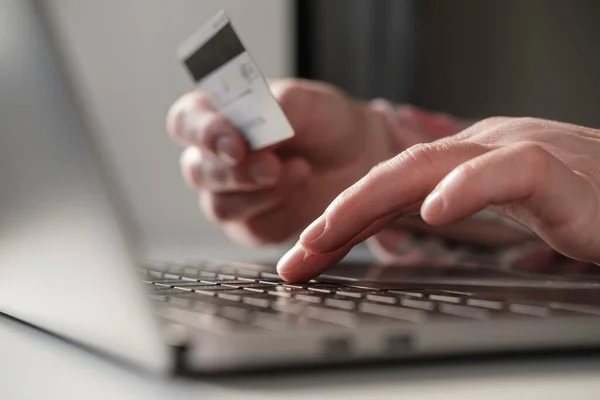 Weibliche Hände geben die Bankdaten einer Kreditkarte auf einem Laptop ein, um Online-Einkäufe zu bezahlen. Konzept der Selbstisolation aufgrund einer Virusepidemie. Moderner Lebensstil. Nahaufnahme. — Stockfoto