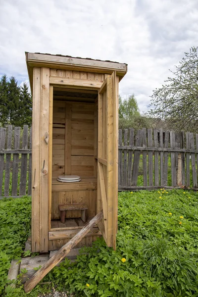 Tradycja, drewniana, rustykalna toaleta, WC, z nowoczesną deską klozetową z pokrywą, na podwórku, na tle starego ogrodzenia. — Zdjęcie stockowe