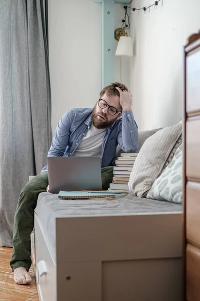 Studenten studerar på distans hemma med en bärbar dator och en bunt böcker. Begreppet online-utbildning under karantän. — Stockfoto