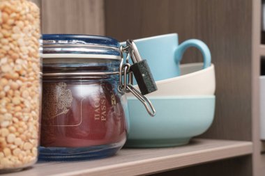 Pasaport kavanozda, kapağı mutfak rafında kilitli. Bir salgın sırasında diğer ülkelere ziyaretleri yasaklama kavramı.