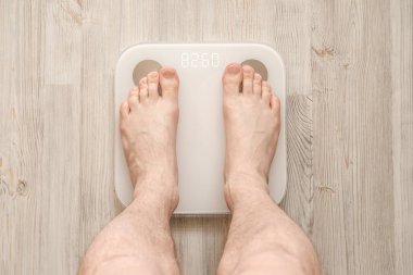 Erkek çıplak ayaklar, biyoelektrik empedans analizi, BIA, vücut yağı ölçümü yapan akıllı teraziler üzerinde dururlar. Üst görünüm.