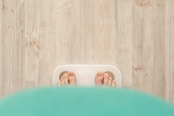 Человек с жировым животом стоит босиком на умных весах, которые делают биоэлектрический анализ импеданса, BIA, измерения жира в организме . Стоковая Картинка