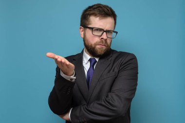 Takım elbiseli bir iş adamı şaşkına döner, kameraya bakar ve elle sorgulama hareketi yapar..