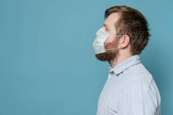 Man with a shaggy beard because of which the medical mask does not fit snugly and does not create full protection. Copy space.