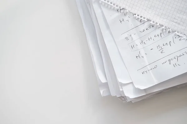 Pilha de papel com registros manuscritos de fórmulas científicas sob uma folha de caderno quadriculado. Espaço para cópia. Vista superior . — Fotografia de Stock
