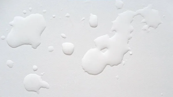 Spillt vatten på en vit strukturerad yta. Bakgrund. Ovanifrån. — Stockfoto