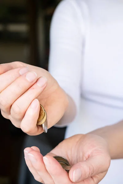 Die weibliche Hand gießt eine kleine Handvoll Münzen in seine Handfläche. Konzept von Krise und Sparen. — Stockfoto