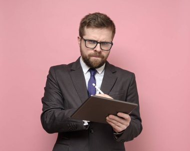 Takım elbiseli ciddi bir adam tabletine stil yazıp şüpheli bir şekilde kameraya bakıyor..