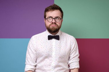 Gücenmiş, üzgün, yuvarlak gözlüklü sakallı adam dudaklarını büzdü ve dikkatlice yukarı baktı..