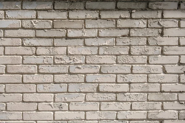 Wall of white brick with peeling off paint outdoors. Background.