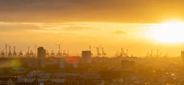 Kranar och vindkraftverk under solnedgången i hamnområdet i Ham — Stockfoto