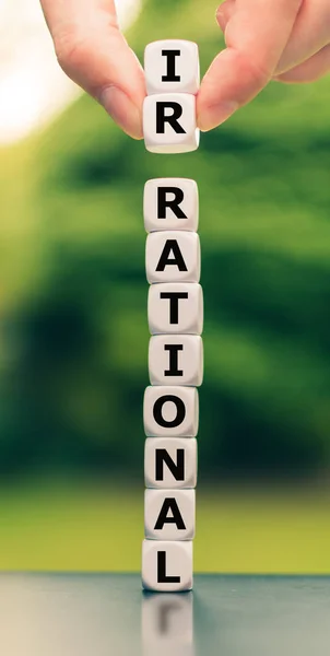 Hand lifts two dice and changes the word "irrational" to "ration — 스톡 사진