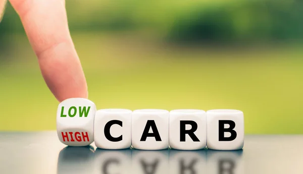 Hand turns a dice and changes the expression from "high carb" to — Stock Photo, Image