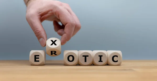 Mão transforma um cubo e muda a palavra "erótico" para "exótico ". — Fotografia de Stock