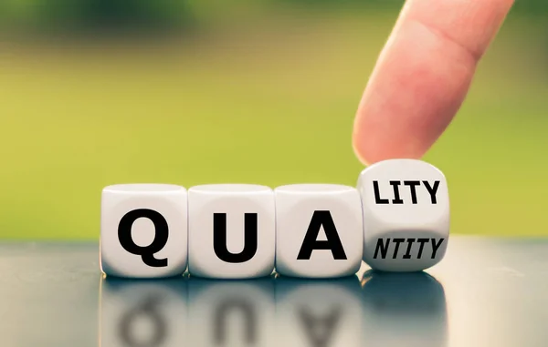 Quality over quantity. Hand turns a dice and changes the word "q — Stock Photo, Image