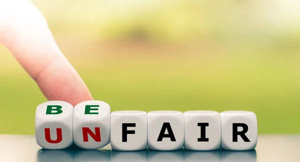 Hand turns a dice and changes the expression "unfair" to "be fai — 스톡 사진