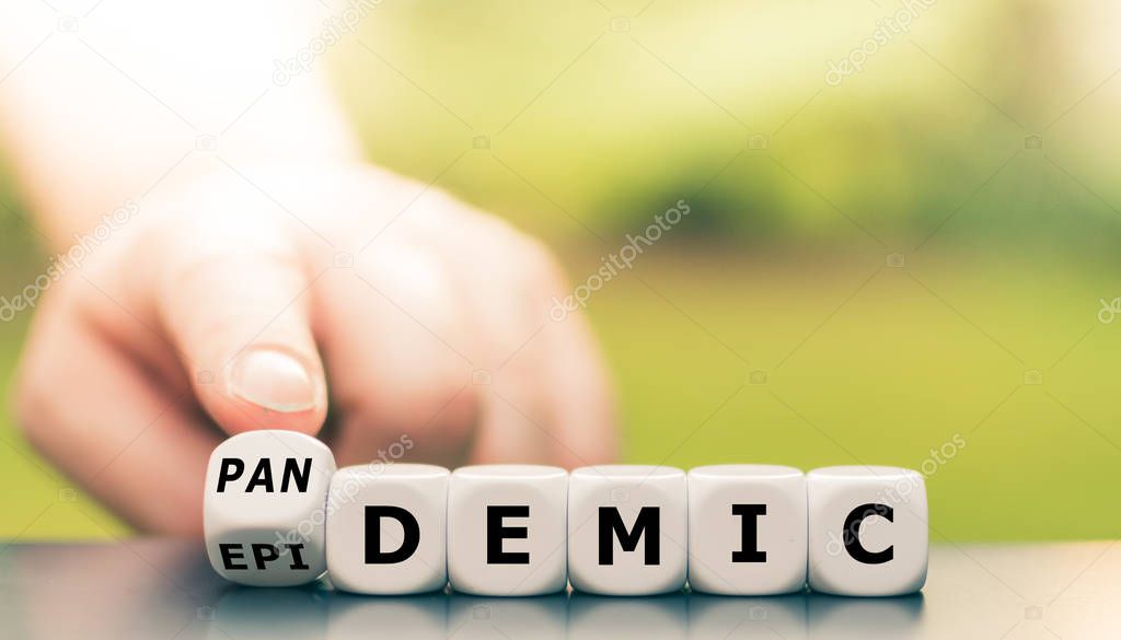 Hand turns a dice and changes the word epidemic to pandemic.
