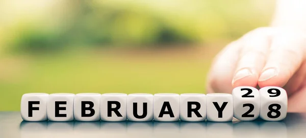 Mão vira dados e muda a data de "28 de fevereiro" para "Febr — Fotografia de Stock