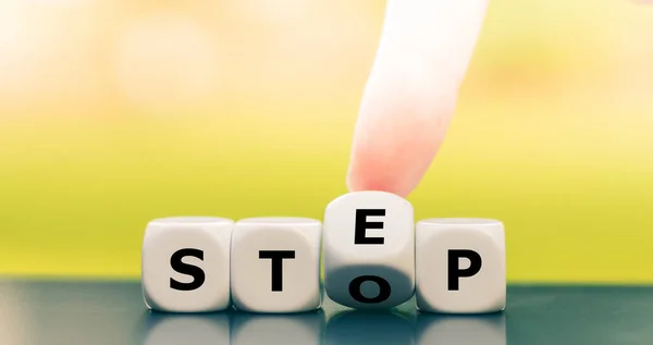 Zrób krok i nie zatrzymuj się. Ręka obraca kostką i zmienia słowo — Zdjęcie stockowe