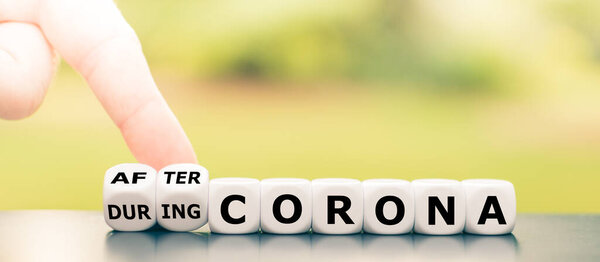 Hand turns dice and changes the expression "during Corona" to "after Corona".