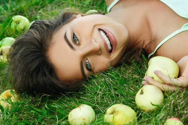 Mujer acostada en la hierba con manzanas — Foto de Stock