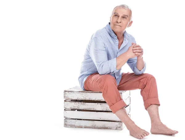 Elderly man sitting on wooden box — Stock Photo, Image