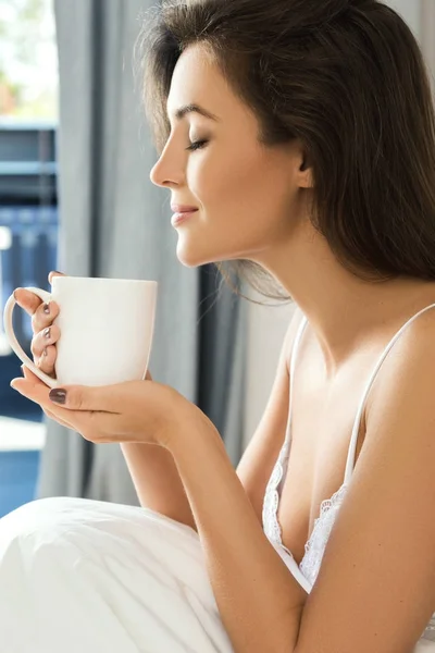 Woman drinking coffee in bedroom — Stock Photo, Image