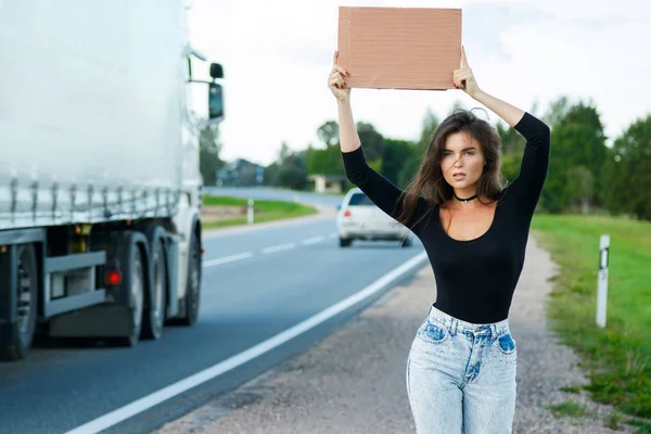 Young woman hitchhiker on road — Stock Photo, Image