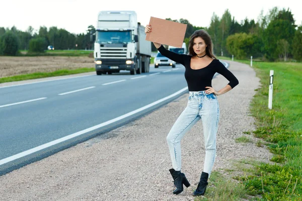 Young woman hitchhiker on road — Stock Photo, Image