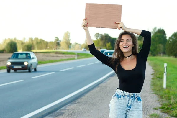 Mujer joven autoestopista en la carretera — Foto de Stock