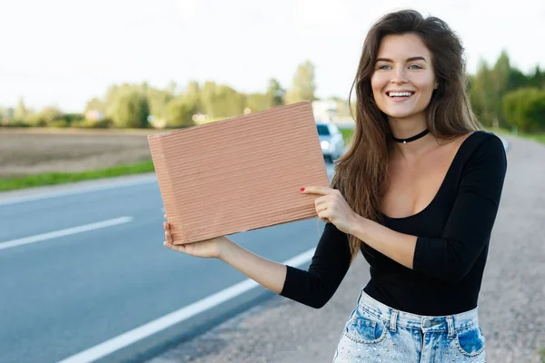 Mujer joven autoestopista en la carretera — Foto de Stock