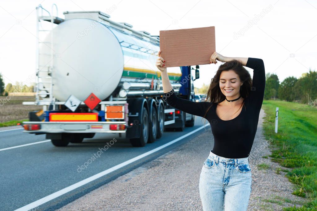 Young woman hitchhiker on road 