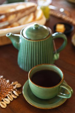 Çaydanlık ve fincanı ahşap masaya yakın tut.