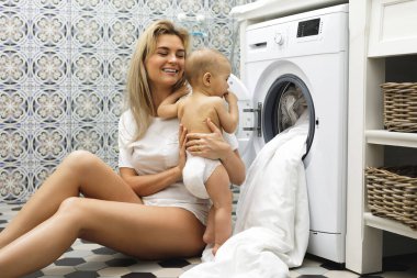 Mutlu anne ve küçük oğlu çamaşır makinesini yüklüyorlar.  